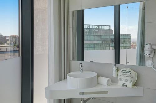 bagno con lavandino e specchio di B&B HOTEL Porto Gaia a Vila Nova de Gaia