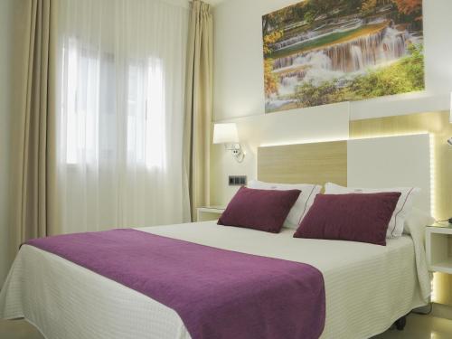 Habitación de hotel con cama grande con almohadas moradas en Hotel Verol, en Las Palmas de Gran Canaria