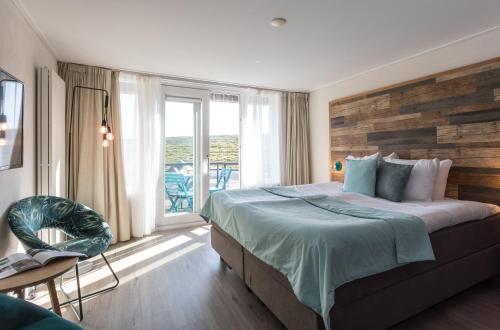 een slaapkamer met een groot bed en een balkon bij Strandhotel Zoutelande in Zoutelande