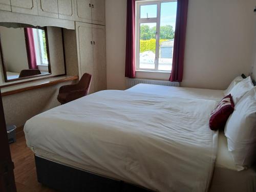 Schlafzimmer mit einem großen weißen Bett und einem Fenster in der Unterkunft Green Acres Self Catering in Claremorris