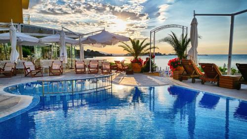 a pool at a resort with chairs and tables at Perla Apartments First Line in Nesebar