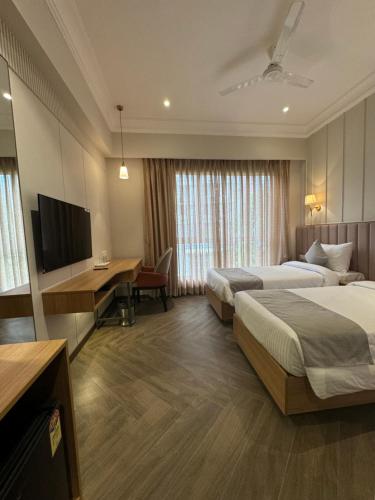 Hotel Mumbai House Mindspace Malad في مومباي: غرفة فندقية بسريرين ومكتب وتلفزيون