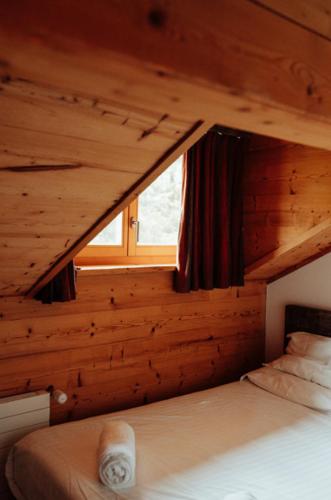 uma cama num chalé de madeira com uma janela em Auberge Restaurant du Lac Retaud em Les Diablerets