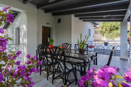 a patio with black chairs and a table with purple flowers at MonteCasa in Epanomi