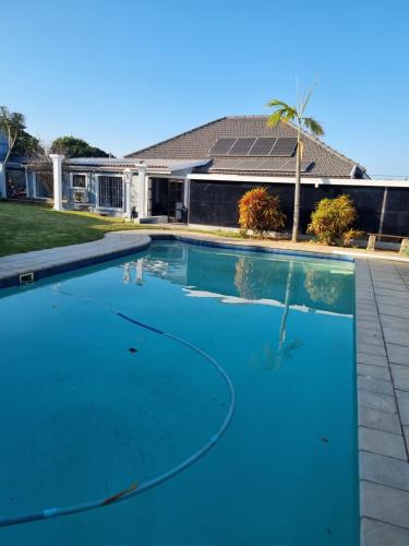 una piscina de agua azul frente a una casa en Troon Harmony - Room 1, en Durban