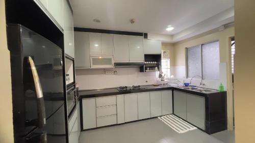 cocina con armarios blancos y nevera negra en Cozy Homestay Putrajaya, en Putrajaya