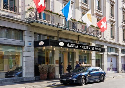 Mandarin Oriental Savoy, Zurich في زيورخ: سيارة متوقفة أمام مبنى به أعلام