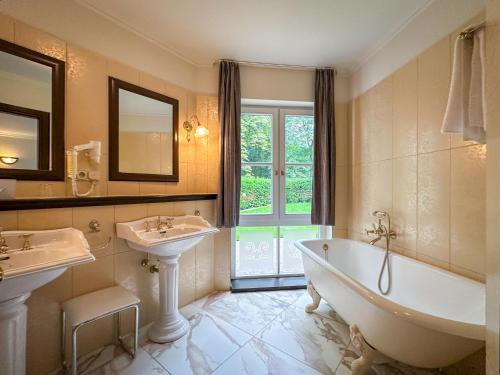 ein Badezimmer mit zwei Waschbecken, einer Badewanne und einer Badewanne in der Unterkunft Weltemühle Hotel by Miri's Dresden in Dresden