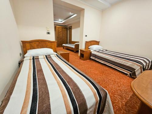 a room with three beds in a room at Garni Hotel BaMBiS in Podgorica