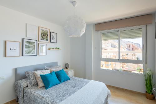 - une chambre avec un lit doté d'oreillers bleus et d'une fenêtre dans l'établissement Apartamento Catania en Aguadulce con vistas al mar, à Aguadulce