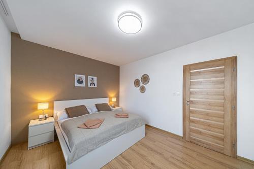 een slaapkamer met een bed en een houten vloer bij Tower Apartments Orchid & Amber in Spišská Nová Ves