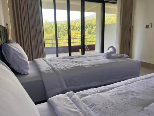 two beds in a bedroom with a large window at Dragonfly Senaru Lodge in Senaru