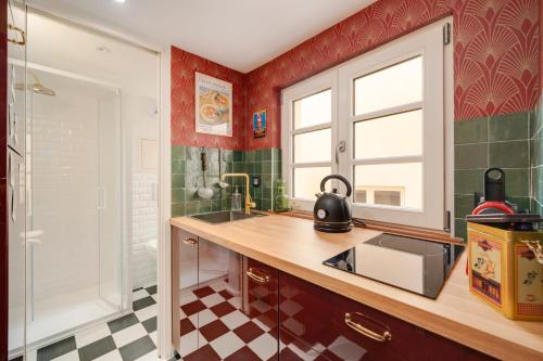 cocina con paredes rojas, lavabo y ventana en L'Appartement d'Amélie, en Nancy