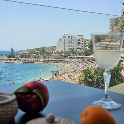 una copa de vino en una mesa junto a la playa en Ares Beachfront Luxury Rooms, en Sarandë