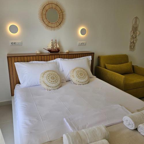 1 cama blanca grande con silla y espejo en Ares Beachfront Luxury Rooms, en Sarandë