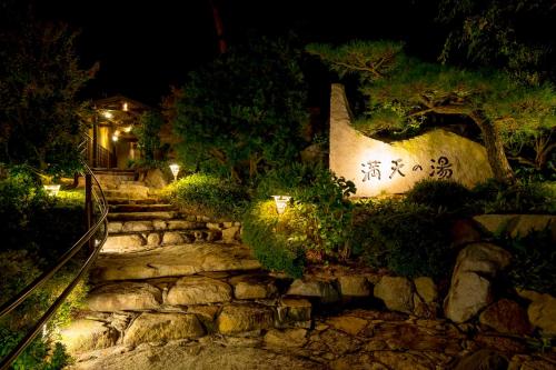 un chemin en pierre menant à une maison la nuit dans l'établissement Sennenmatsu, à Imabari