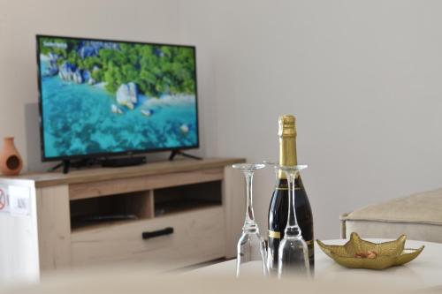 two bottles of wine on a table in front of a television at KenDar Premium Apartments in Ulcinj