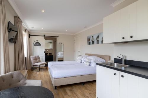 a white bedroom with a bed and a kitchen at Villa Zuiderduin in Zoutelande