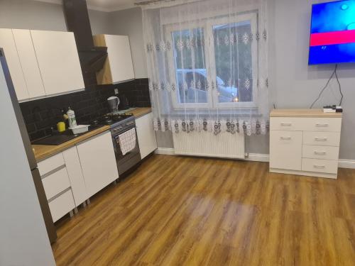 Il comprend une cuisine avec des placards blancs et du parquet. dans l'établissement Apartament mieszkanie do wynajęcia Nicola, à Wałbrzych