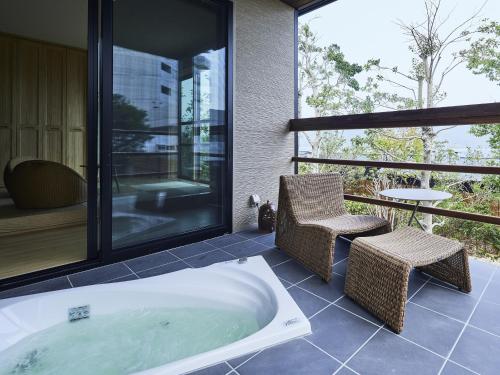 een badkamer met een bad en een tafel en stoelen bij 宮島離れの宿 IBUKU 別邸 -Miyajima Hanarenoyado IBUKU Bettei- in Ōno