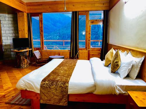 The Vashisht, Manali - A Four Star Luxury Hotel في مانالي: غرفة نوم بسرير كبير مع نافذة كبيرة