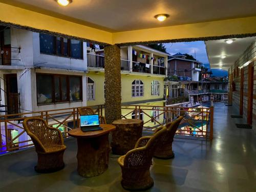 The Vashisht, Manali - A Four Star Luxury Hotel في مانالي: شرفة مع كراسي وجهاز كمبيوتر محمول على طاولة