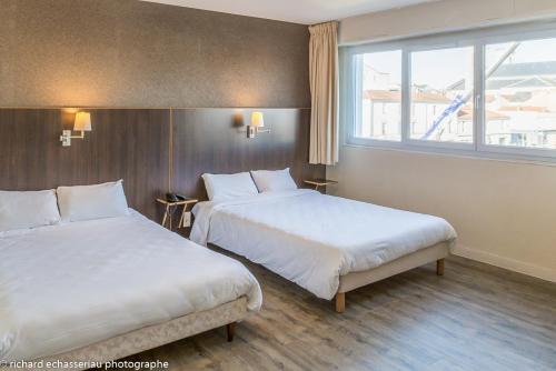 A bed or beds in a room at Hôtel de la Vendée