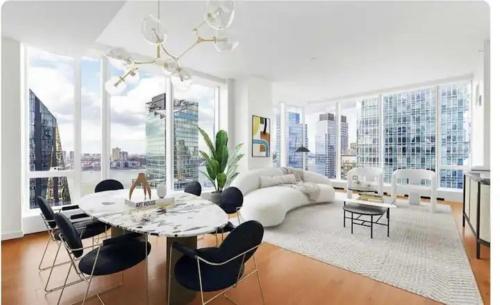 een woonkamer met een witte bank en een tafel en stoelen bij Stunning views of Manhattan in New York