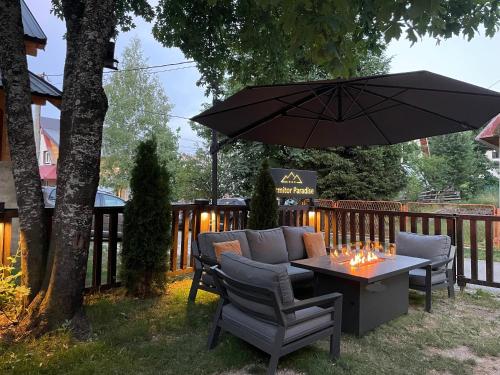 un patio con mesa, sillas y sombrilla en Guest House Durmitor Paradise, en Žabljak