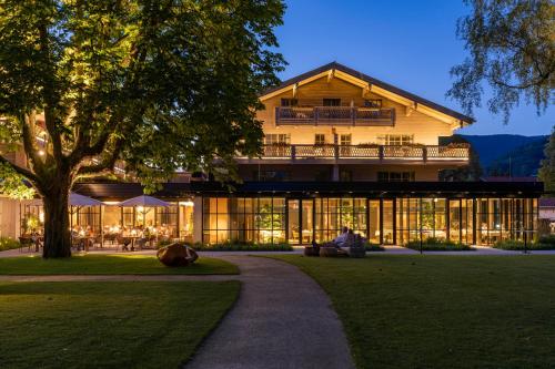 un homme assis devant un bâtiment dans l'établissement Parkhotel Egerner Höfe, à Rottach-Egern