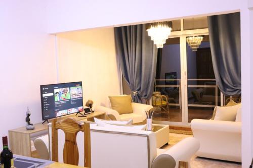 uma sala de estar com mobiliário branco e uma televisão em Sunset view Suite em Trou dʼ Eau Douce