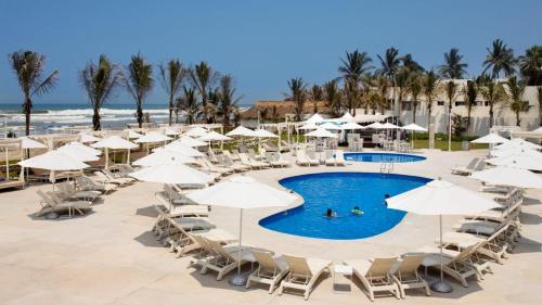 uma piscina com cadeiras e guarda-sóis na praia em Palacio Mundo Imperial Riviera Diamante Acapulco All Inclusive em Acapulco