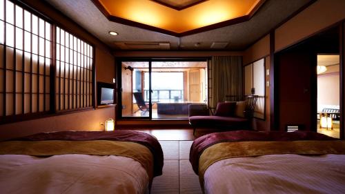 a hotel room with two beds and a living room at Aburaya Tousen in Yamanouchi