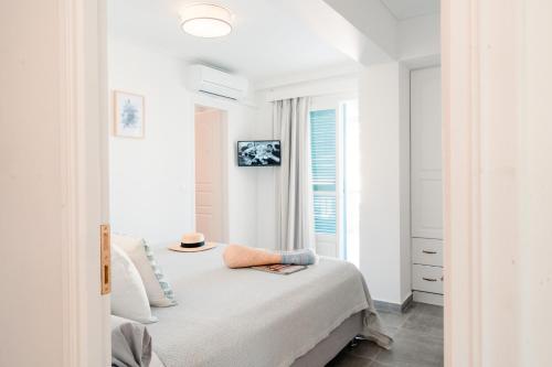 a white bedroom with a bed and a window at Nikis Village in Poros