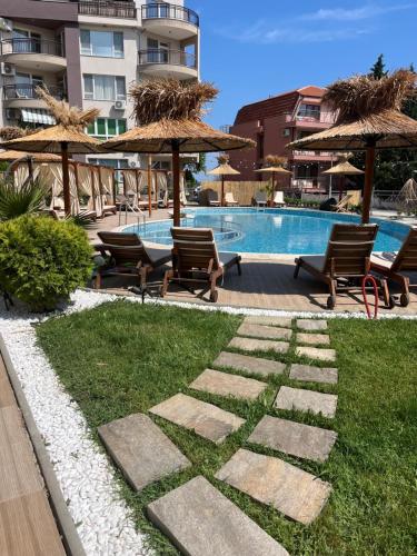 una piscina con sillas y sombrillas junto a un césped en Apartment & Studio Traky, Saint Vlas, улица Черно Море 12, en Sveti Vlas