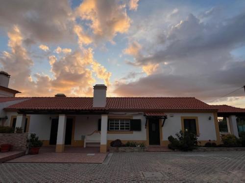 uma casa com um céu nublado na frente dela em Quinta do Marmeleiro em Santiago do Cacém