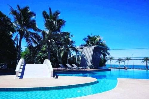 a swimming pool with palm trees and a resort at studio room seaview jomtien in Jomtien Beach