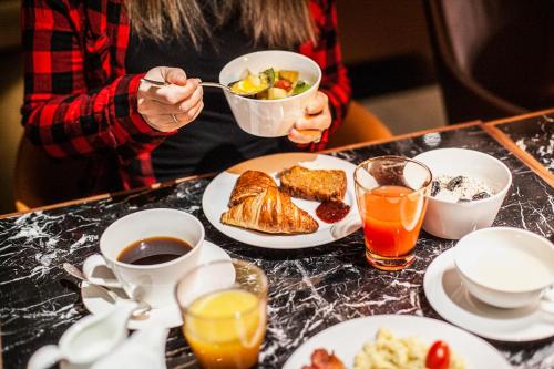 a woman eating a bowl of breakfast food on a table at Schweizerhof Zermatt - a Small Luxury Hotel in Zermatt