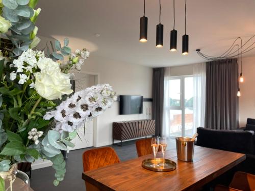 sala de estar con mesa de comedor con flores en Stadthafenapartments, en Rostock