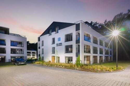 a building with a car parked in front of it at Sea Shell Apartments Łukęcin in Łukęcin