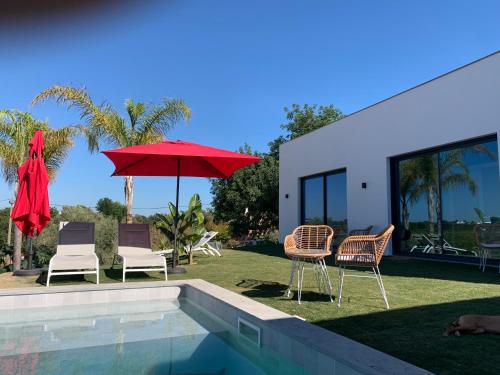 - un groupe de chaises et un parasol à côté de la piscine dans l'établissement B&B Quinta a Fonte Tavira - Adults Only, à Tavira