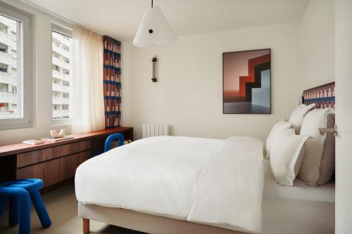 a bedroom with a large white bed and a desk at Edgar Suites Montrouge in Montrouge