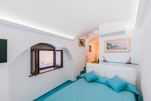 um quarto com uma cama com almofadas azuis e uma janela em B&B IL CORTILE em Ravello