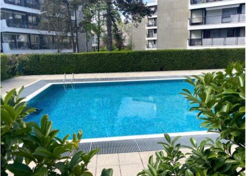 uma grande piscina azul em frente a um edifício em Cosy Apartment at Mérignac-centre em Mérignac