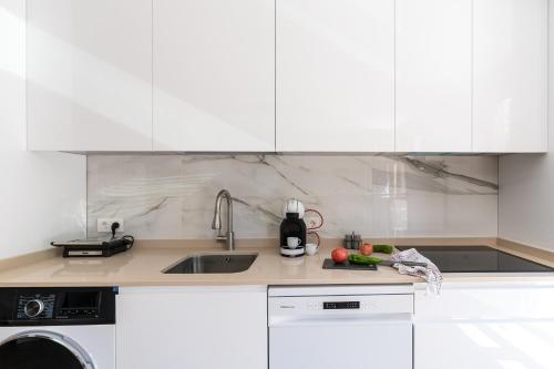 a kitchen with white cabinets and a sink with fruits and vegetables at Acogedor Refugio con Terraza in Alcalá de Henares