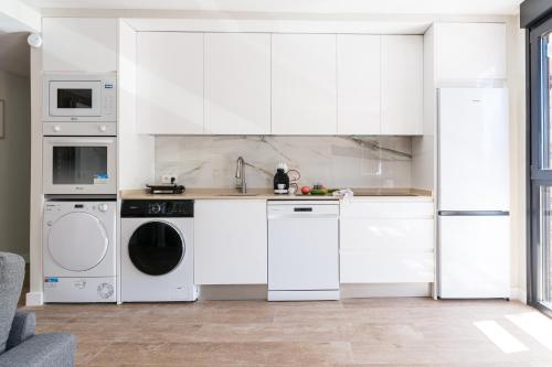 a kitchen with white cabinets and a washer and dryer at Acogedor Refugio con Terraza in Alcalá de Henares