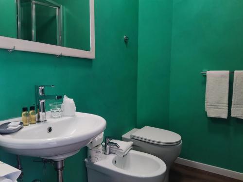 een groene badkamer met een wastafel en een toilet bij Ristorante Albergo Dante in Montefiascone