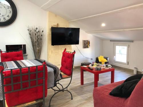 a living room with red furniture and a clock on the wall at Le Logis de Virginie - climatisé in Rochefort