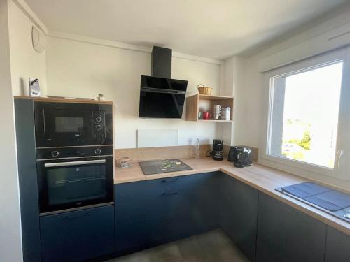 una cucina con armadi blu, lavandino e forno a microonde di Appartement spacieux Brest Bellevue de 1 à 6 personnes a Brest