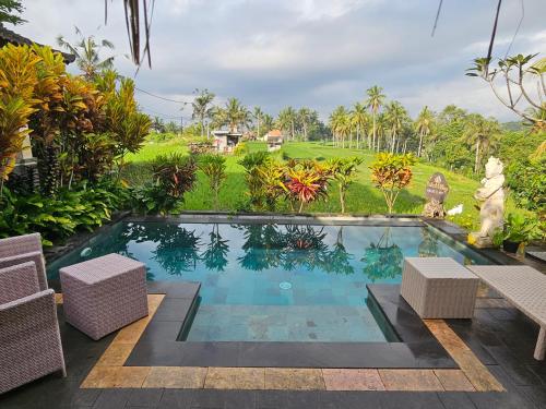 una piscina en un jardín con 2 sillas en Dukuh Village Villas & Art, en Tegalalang